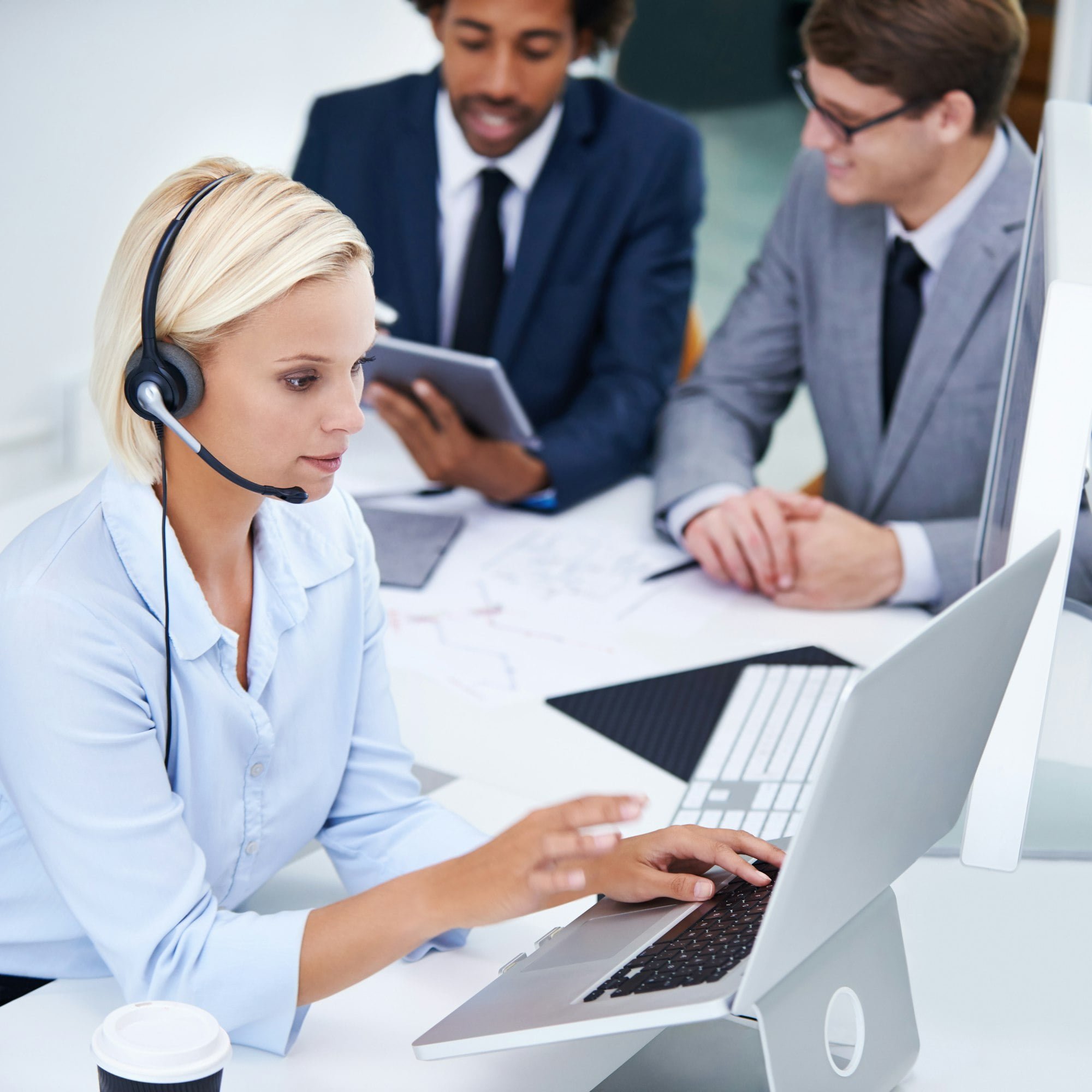 Shot of a businesswoman working on her laptop with colleagues in the background